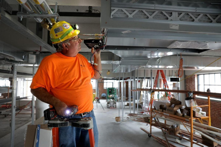 Bob Stith, a pipefitter with Local 562, installs a fan coil unit for the air conditioning on Tuesday, May 21, 2019, on the first floor of the newest Cortex complex building at 4340 Duncan Ave. in St. Louis' Central West End.